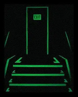 Photoluminescent markings on stair edges, handrails and an exit door glowing green in the dark along an escape route